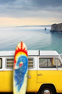 Una camioneta amarilla con una tabla de surf en la playa