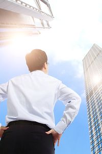Symbolic careers picture of a man standing in front of a skyscraper looking upwards into the sky